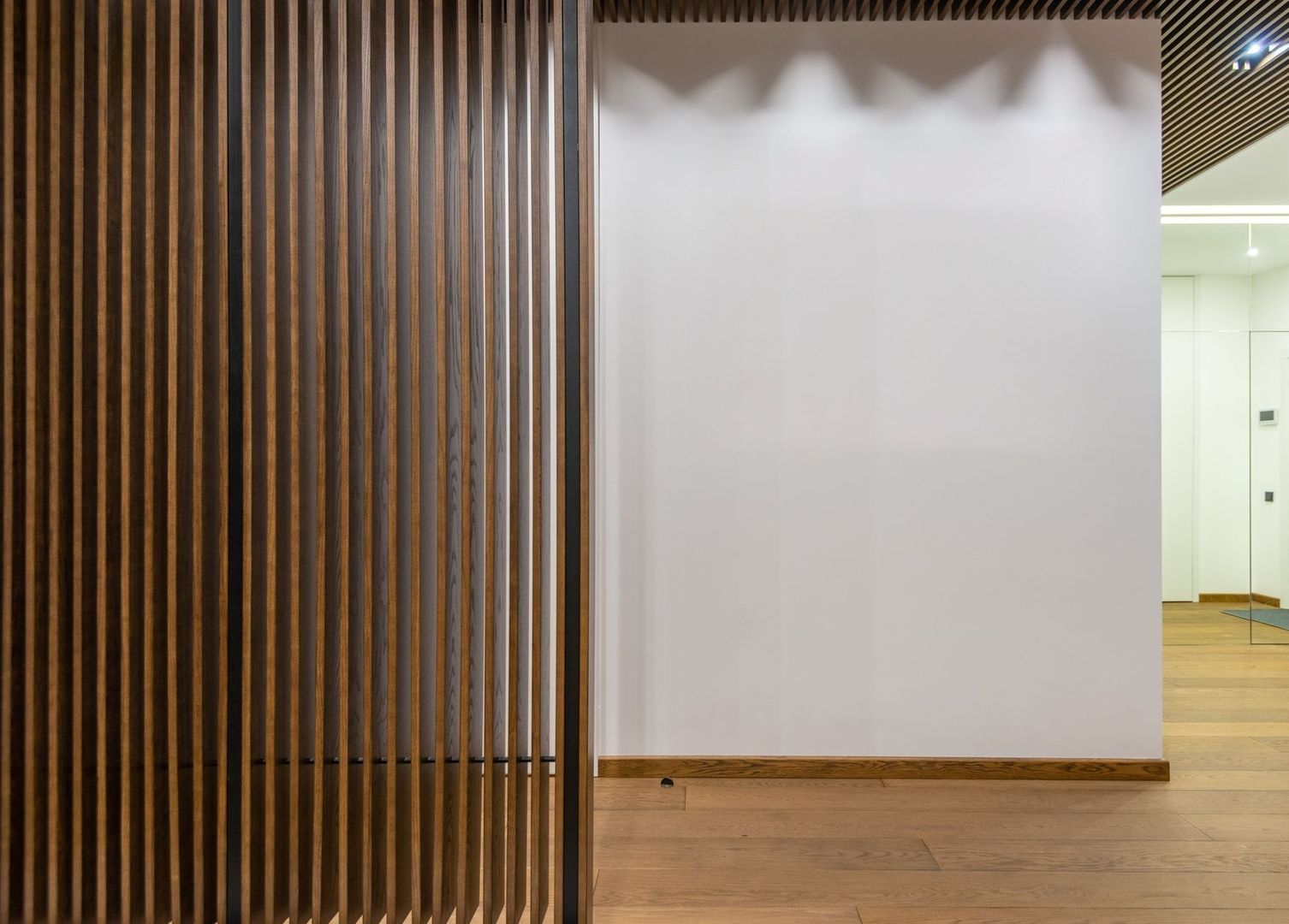 Moderne Wand mit vertikalen Holzlamellen und weißer Fläche
